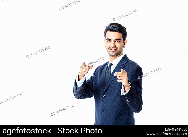 Portrait of a smiling businessman in black suit and tie pointing at camera with both hands isolated on white background