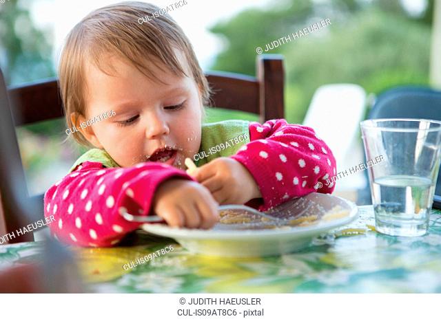 Female toddler eating at table
