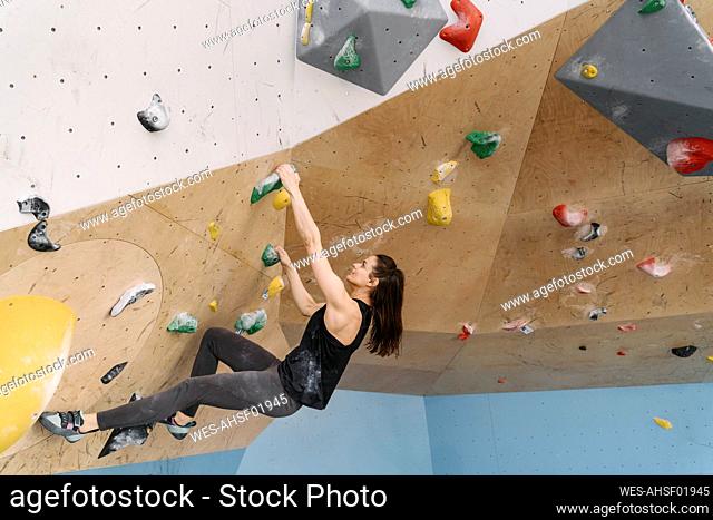 Woman bouldering in climbing gym