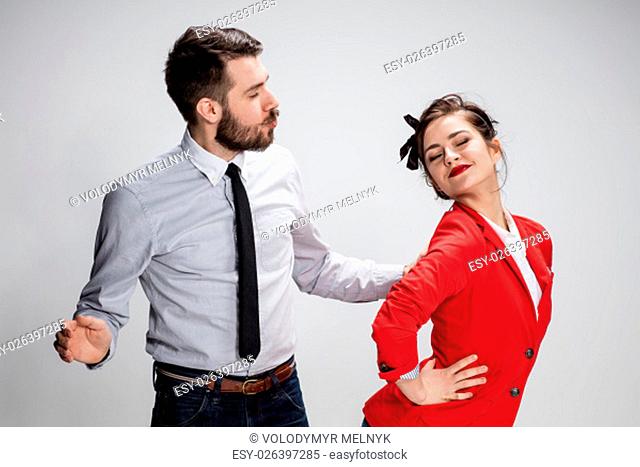 The funny business man and woman communicating on a gray background. Business concept of relationship of colleagues