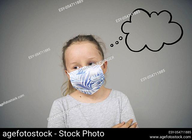 girl trying to stay healthy by wearing a mask to protect him against corona virus covid-19 while looking at copyspace with thought bubble