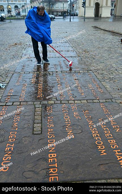 04 November 2021, Brandenburg, Potsdam: An employee of the Office of Public Order cleans the lettering on Luisenplatz to commemorate the fall of 1989