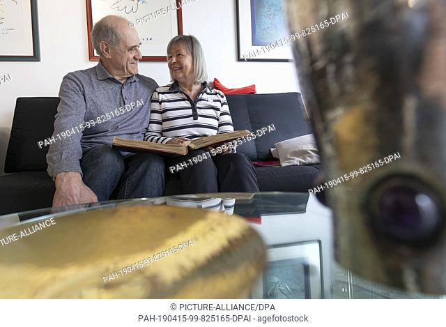 11 April 2019, Hessen, Bruchköbel: As they leaf through an old photo album, Waldemar and Edith Wolf sit on the sofa in their shared apartment
