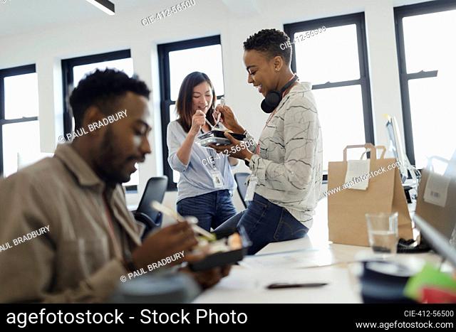 Business people eating takeout lunch at desk in office