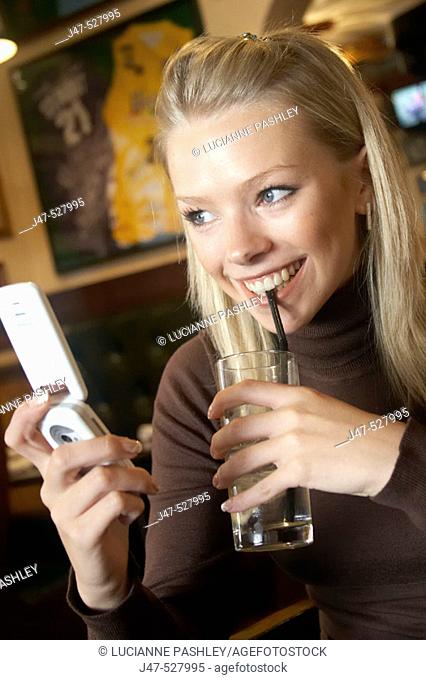 21 year old girl in a cafe on her mobile phone, smiling