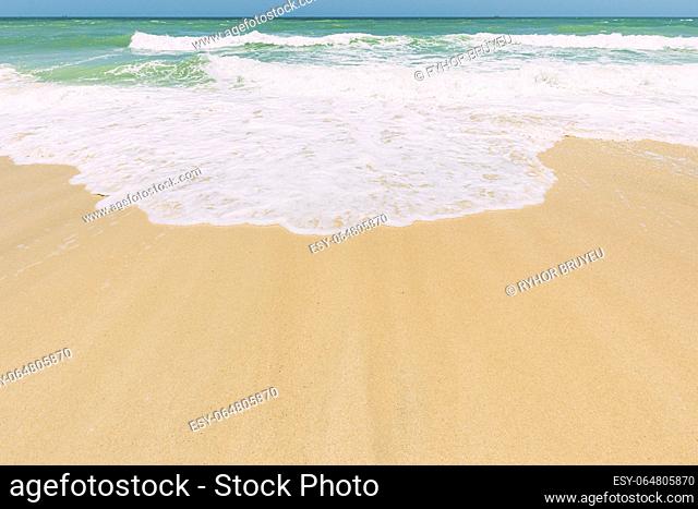 Ocean water foam splashes washing sandy beach. Amazing landscape scenery. Crashing waves of sandy coastline. Sea ocean water surface with small waves