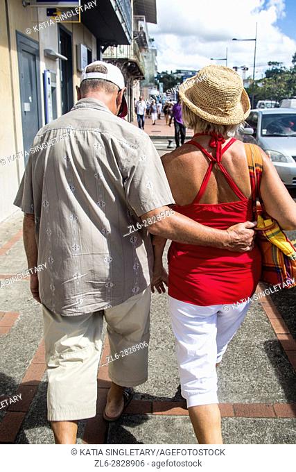 Older mature couple holding each other back, being in love, while strolling the streets of Fort De France