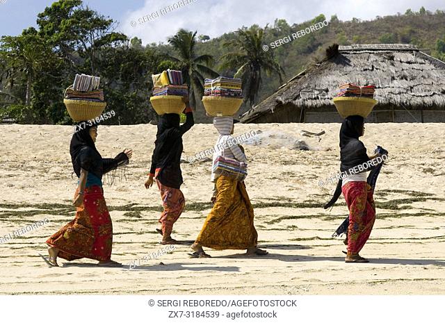The women walk along the beach of Kuta, a fishing village south of Lombok, in search of a tourist who wants to buy their souvenirs