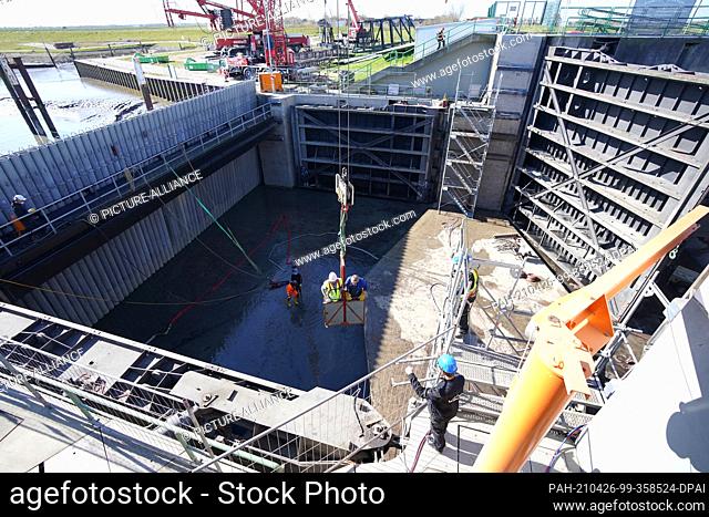 26 April 2021, Schleswig-Holstein, Husum: Workers prepare a gate of the barrage for crane lifting. On Monday, the gates of the Husum barrage were lifted out of...