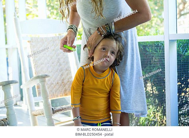 Caucasian mother applying sunscreen to face of son