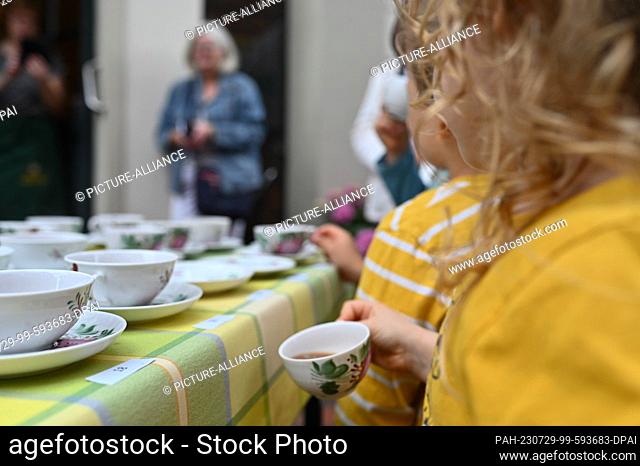 29 July 2023, Lower Saxony, Leer: A young guest enjoys a cup of East Frisian tea. Record attempt at the Bünting Tea Museum: serving 200 cups of East Frisian tea...