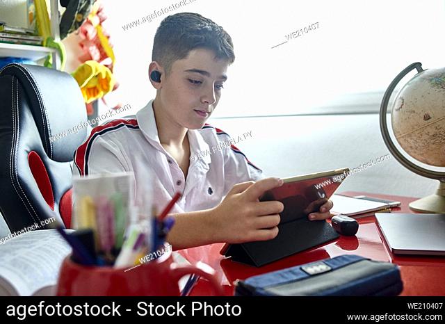 teenager teaching online classes and doing his homework in his study room