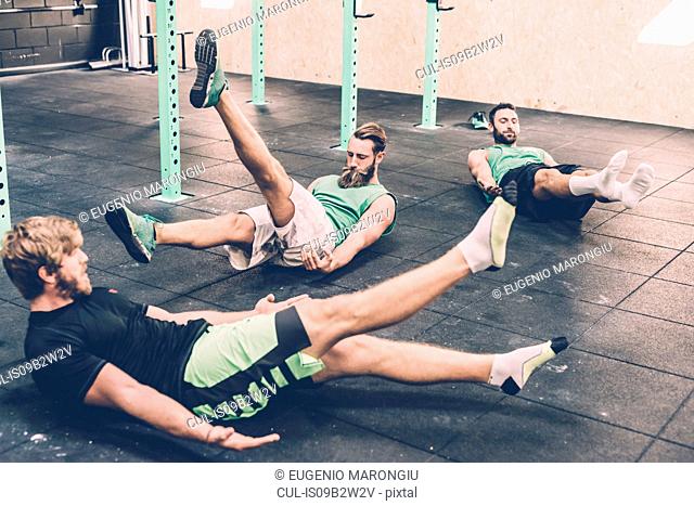 Three male cross trainers doing warm ups in gym