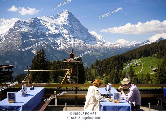Couple sitting on terrace of the mountain restaurant Berghaus Bort 1600 m, First, Eiger 3970 m in background, Grindelwald, Bernese Oberland highlands
