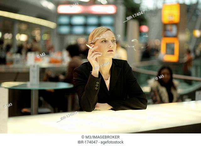 Young woman smoking at an airport café