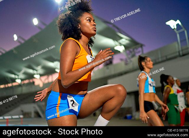 Focused female track and field athlete preparing for race in stadium