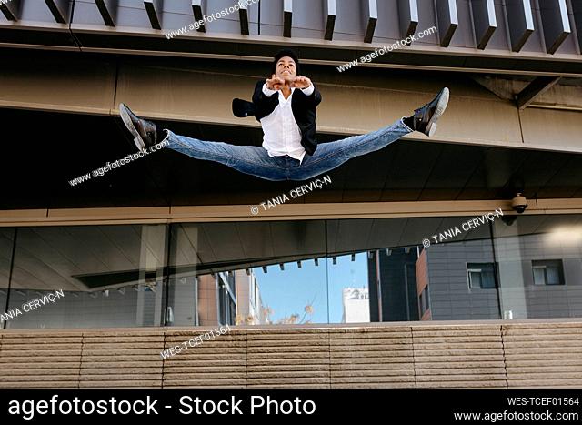 Male entrepreneur dancing while doing splits in mid-air
