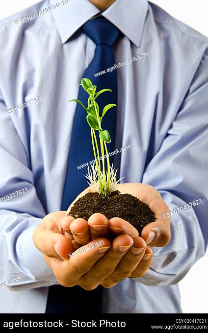 Young student holding green seedlings on white
