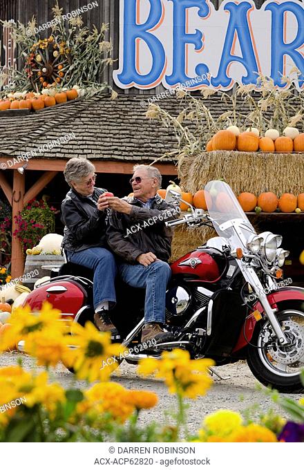 Motorcycle touring couple stops at a fruit stand in Keremeos in the Similkameen region of British Columbia, Canada