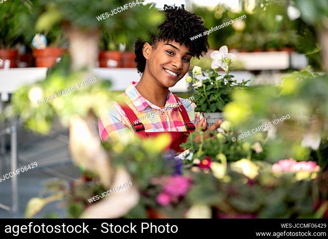 Smiling florist showing plant at nursery
