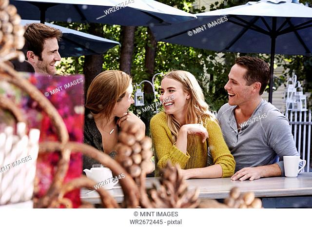 A group of people sitting at a long table in an outdoor cafe