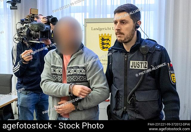 21 December 2023, Baden-Württemberg, Ulm: A court constable leads a handcuffed man into the courtroom at the regional court