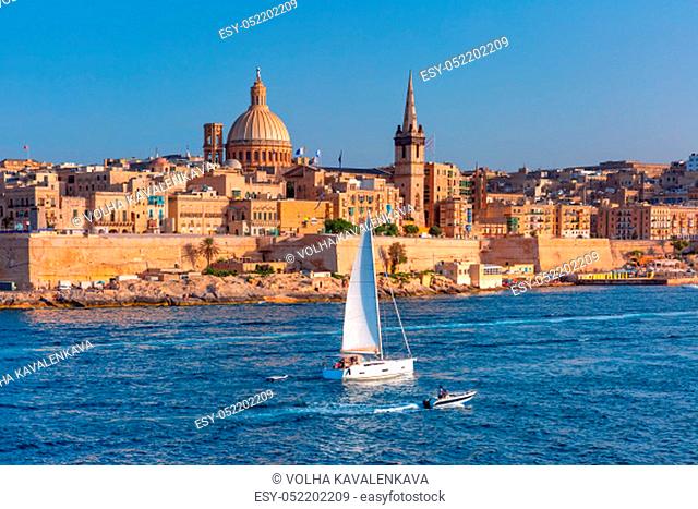 White yacht and Old town of Valletta with churches of Our Lady of Mount Carmel and St. Paul's Anglican Pro-Cathedral, Valletta, Capital city of Malta