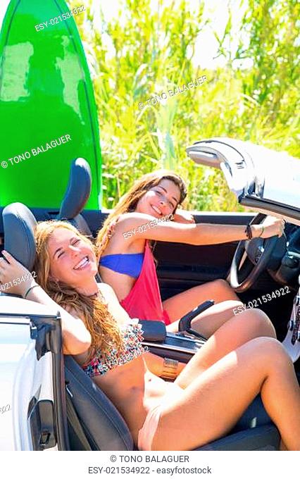 Happy crazy teen surfer girls smiling on car