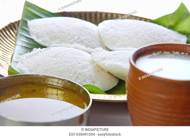 Idli in a plate with sambar and lassi