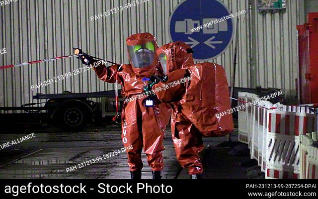 13 December 2023, Berlin: Firefighters in special suits work on the premises of a waste disposal company in Berlin-Rudow