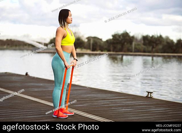 Sportswoman stretching resistance band on jetty