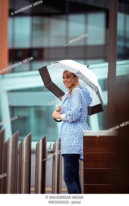 Beautiful woman holding umbrella and standing on street