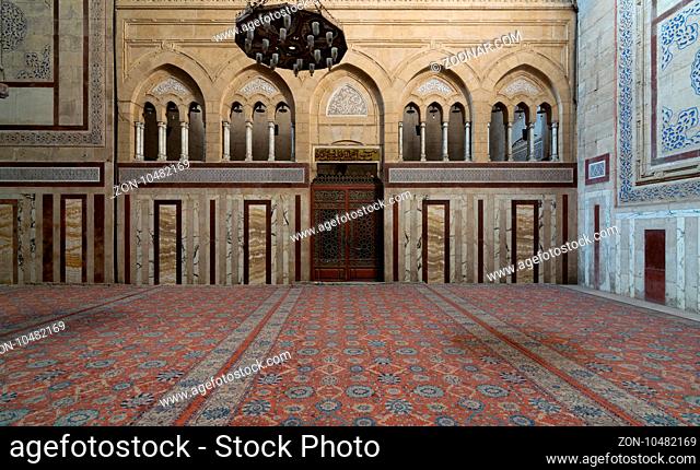 Interior shot of Al Rifaii Mosque (Royal Mosque) with iron chandelier, decorated marble wall and ornate wooden door, located in front the Cairo Citadel, Cairo