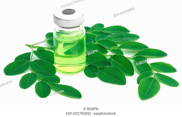 Moringa leaves with extract in a vial over white background