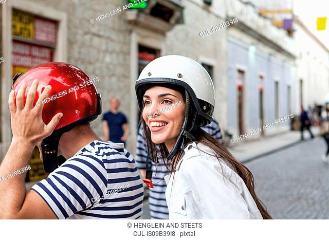 Young couple riding moped through village, Split, Dalmatia, Croatia