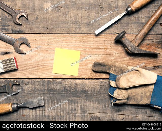 Old used tools with a sticky note on a workbench with space for text