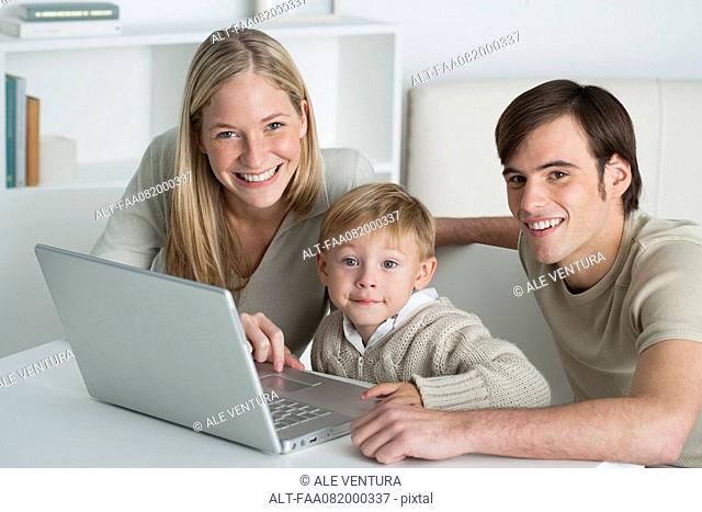 Young parents and little boy with laptop computer, portrait