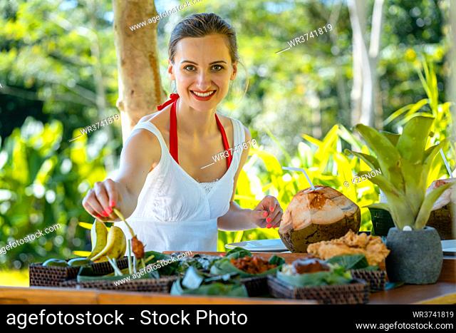 Woman having lunch in tropical setting during her vacation choosing from the dishes