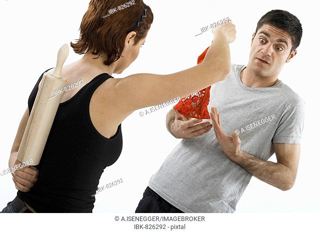 Woman holding a pair of red panties accusingly in front of a man