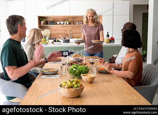 Group of senior friends having a good time and enjoying a meal togehter at home