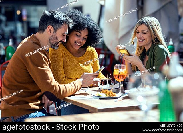 Male and female friends using mobile phones at restaurant