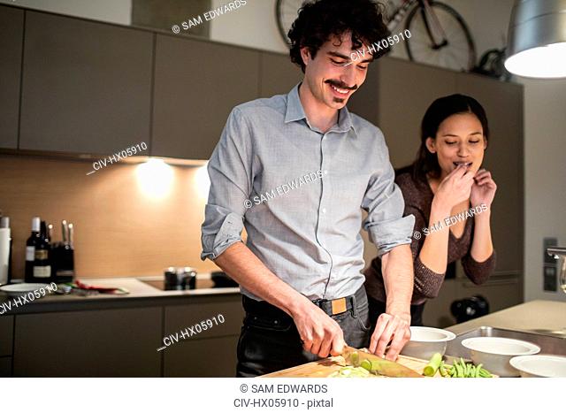 Couple cutting vegetables, preparing dinner in apartment kitchen