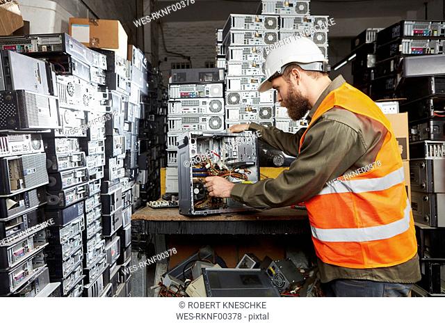 Worker in computer recycling plant dismounting desktop pc