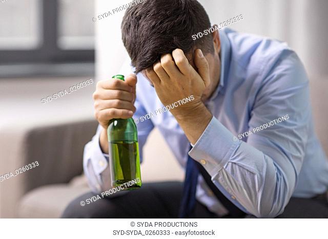 male alcoholic drinking beer at home