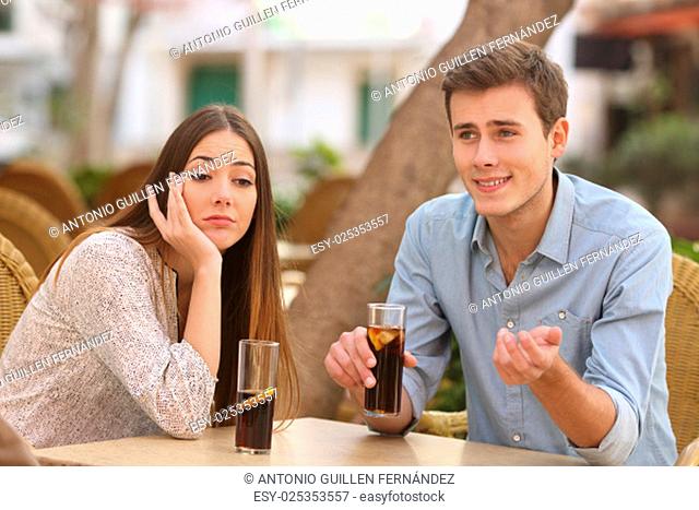 Man and woman dating in a restaurant terrace but she is boring while he speaks