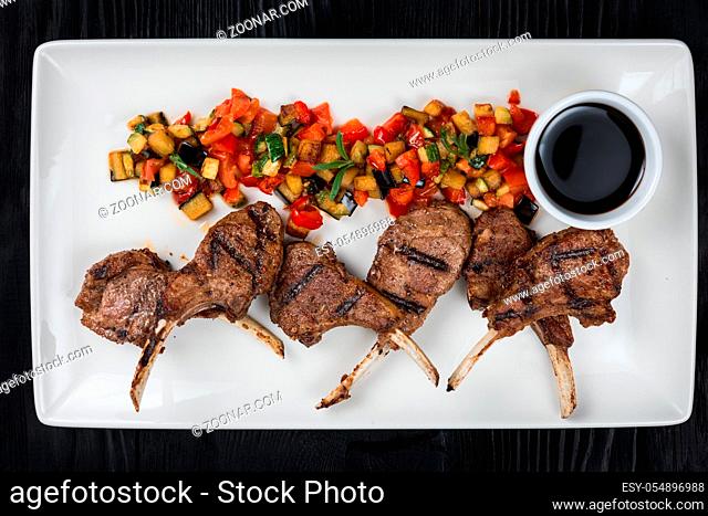 Roasted lamb ribs with vegetables on white palte