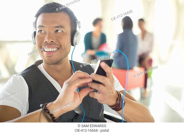 Casual businessman listening to music on headphones with mp3 player