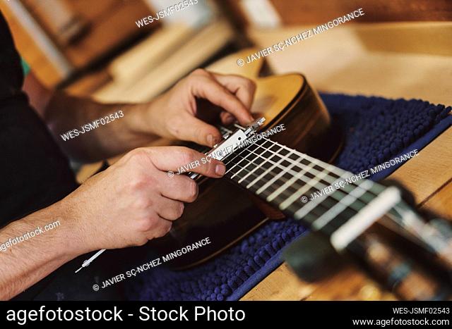 Hands of craftsman working on guitar in workshop