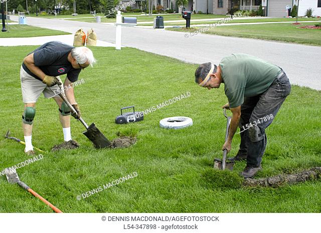 Two retired adult men working in second career install lawn irrigation