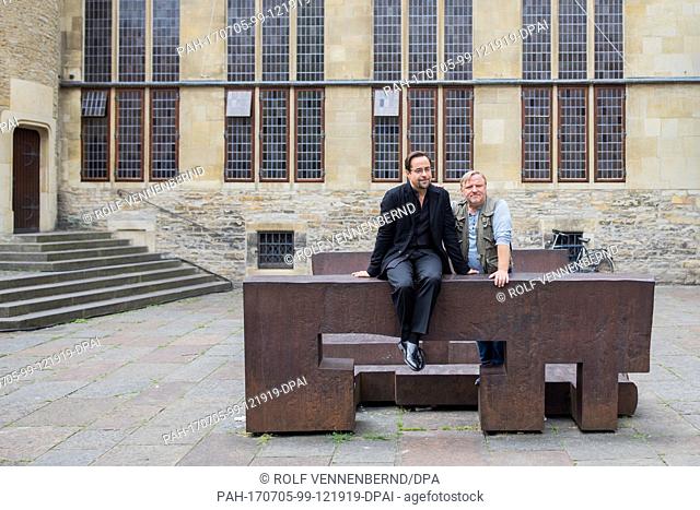 The actors Jan Josef Liefers (L) and Axel Prahl pose on the two benches by artist Eduardo Chillida at the shooting of the new 'Tatort' from Muenster, Germany